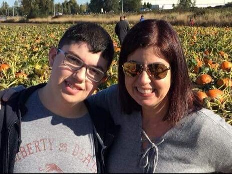 Dr. Lanya McKittrick (wearing sunglasses) with son Connor smiling and standing in a pumpkin patch